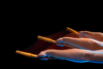 Image showing The arm with wooden baseball bat on black background