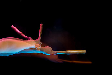 Image showing The arm with wooden baseball bat on black background