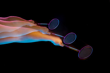 Image showing The hands of young man playing badminton over black background