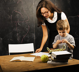 Image showing little cute boy in glasses with young real teacher, classroom studying