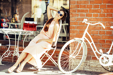 Image showing young pretty brunette woman after shopping sitting at cafe outside on street smiling