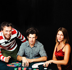 Image showing young people playing poker on black background