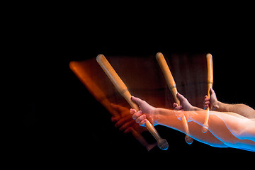 Image showing The arm with wooden baseball bat on black background