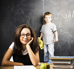 Image showing little cute boy in glasses with young real teacher, classroom studying