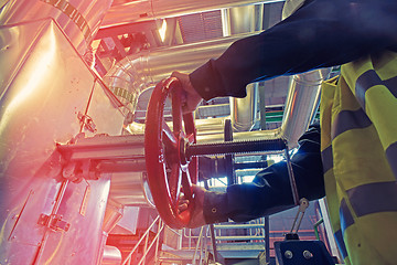 Image showing industrial factory worker turning red wheel of valve