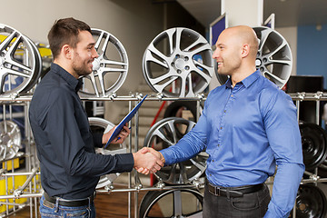 Image showing auto business owner and wheel rims at car service