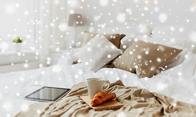 Image showing tablet pc, coffee and croissant on bed at home