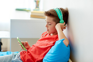 Image showing happy boy with smartphone and headphones at home