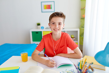 Image showing happy student boy writing to notebook at home