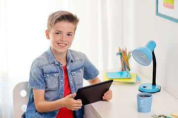 Image showing smiling boy with tablet pc sitting at home desk