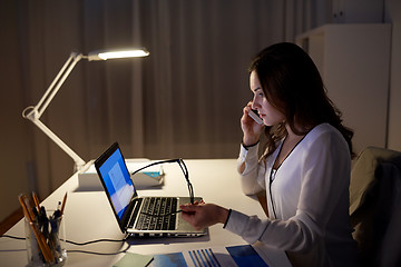 Image showing woman with laptop calling on smartphone at office