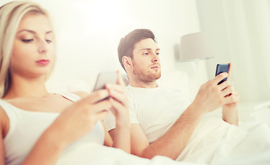 Image showing couple with smartphones in bed