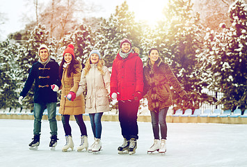 Image showing happy friends ice skating on rink outdoors