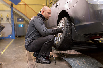 Image showing auto mechanic changing car tire at workshop