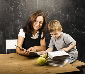 Image showing little cute boy in glasses with young real teacher, classroom studying