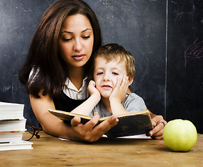 Image showing little cute boy in glasses with young real teacher, classroom studying