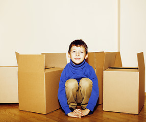 Image showing little cute boy in empty room, move to new house. home alone among boxes close up kid smiling, lifestyle real people concept