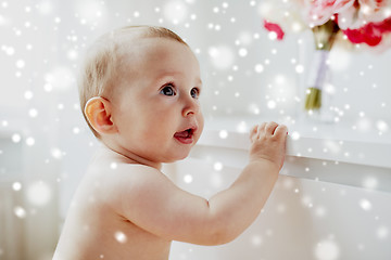 Image showing happy little baby boy or girl holding to table