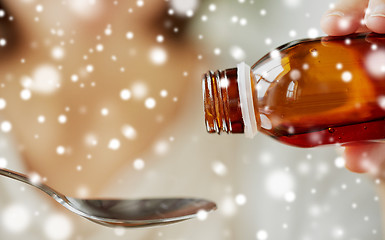 Image showing woman pouring medication from bottle to spoon