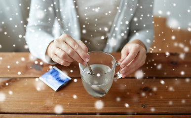 Image showing ill woman stirring medication in cup with spoon