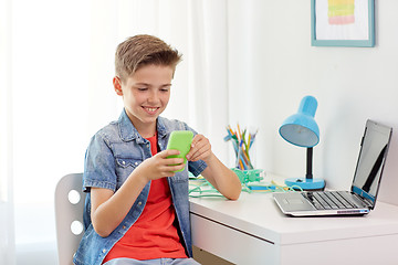 Image showing happy boy with smartphone and laptop at home