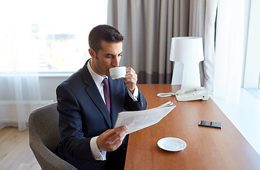 Image showing businessman reading newspaper and drinking coffee