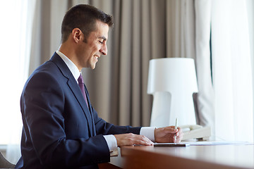 Image showing businessman with papers working at hotel room