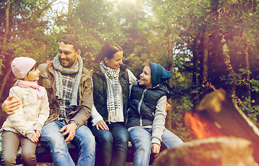 Image showing happy family sitting on bench at camp fire