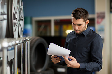 Image showing auto business owner and wheel rims at car service