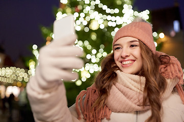 Image showing young woman taking selfie over christmas tree