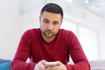 Image showing young man using a mobile phone  at home