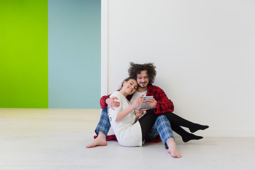 Image showing Young Couple using digital tablet on the floor