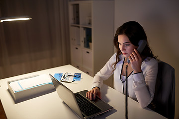 Image showing woman with laptop calling on phone at night office