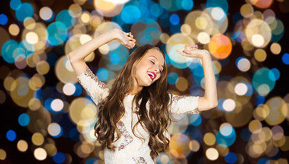 Image showing happy young woman dancing over party lights