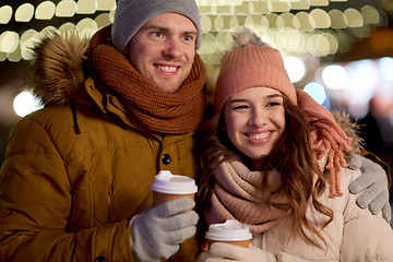 Image showing happy couple with coffee over christmas lights