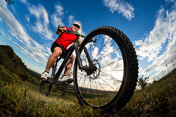 Image showing cyclist riding mountain bike on rocky trail at sunrise