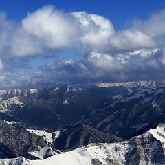 Image showing Sunlit winter mountains in clouds, view from off-piste slope