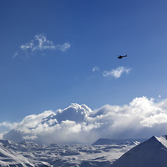 Image showing Helicopter above snowy plateau and sunny sky