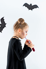 Image showing Little girl witch in black dress over magical accessories. Halloween, the studio evening.