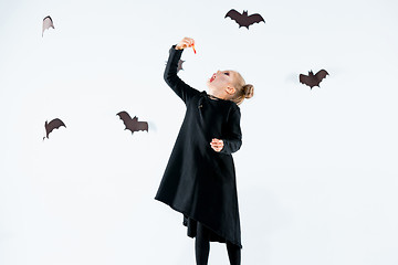 Image showing Little girl witch in black dress over magical accessories. Halloween, the studio evening.