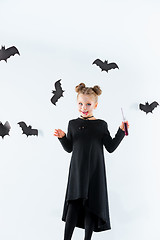 Image showing Little girl witch in black dress over magical accessories. Halloween, the studio evening.