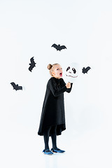 Image showing Little girl witch in black dress over magical accessories. Halloween, the studio evening.