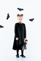 Image showing Little girl witch in black dress over magical accessories. Halloween, the studio evening.