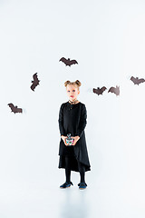 Image showing Little girl witch in black dress over magical accessories. Halloween, the studio evening.