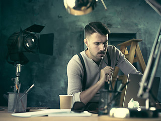 Image showing Portrait of a bearded businessman who is checking details of his upcoming meeting in his notebook and typing.