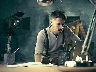 Image showing Portrait of a bearded businessman who is checking details of his upcoming meeting in his notebook and typing.