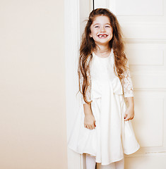 Image showing little cute girl at home, opening door well-dressed in white dre