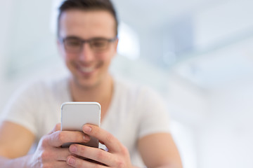 Image showing young man using a mobile phone  at home