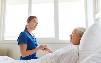 Image showing doctor or nurse visiting senior woman at hospital