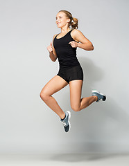 Image showing young woman in black sportswear jumping